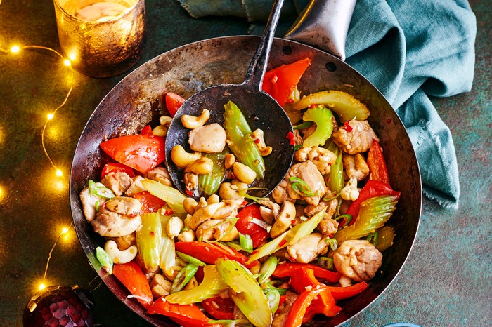 A wok full of chicken, vegetables, celery and toasted cashews