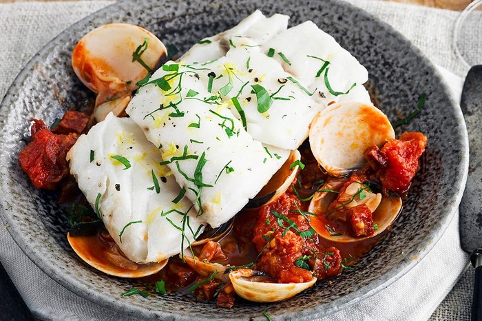 Plate of Skrei fillets on a bed of clams and chorizo in tomato sauce