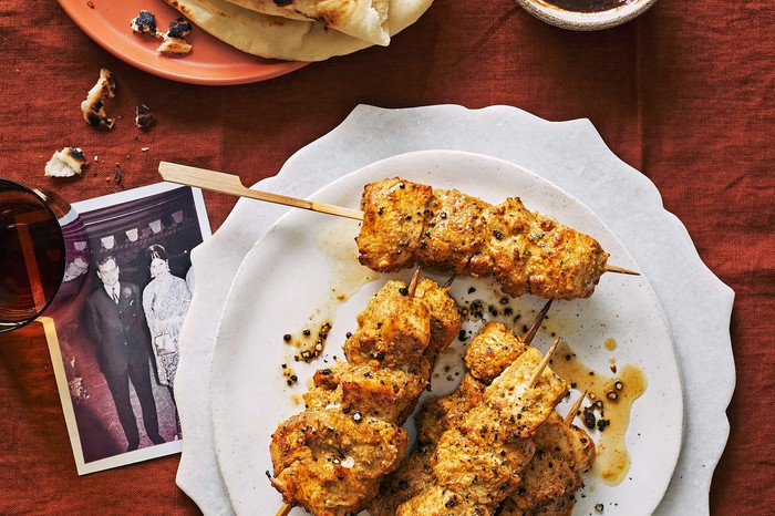 Skewered marinaded chicken sticks on a white plate