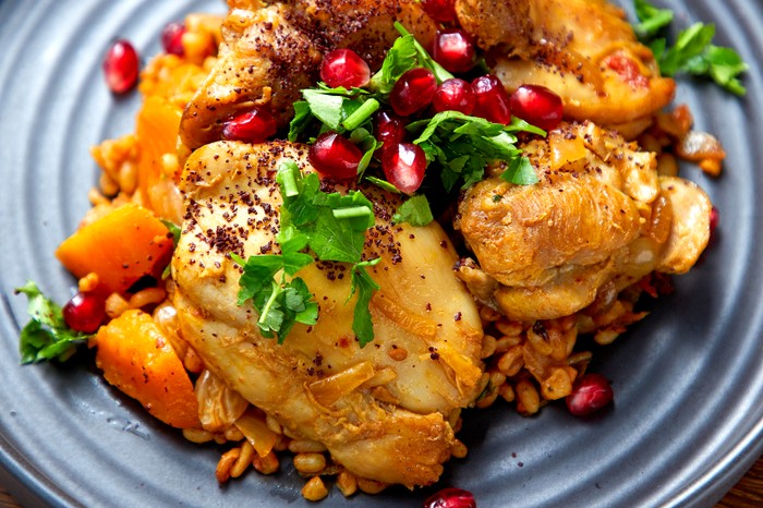 A chicken thigh dish topped with pomegranates