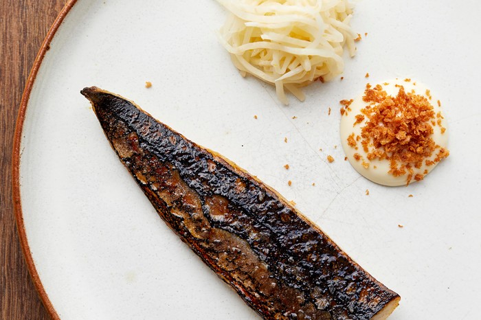 Mackerel Recipe with Celeriac and Lemon served on a off-white round plate on a dark brown wooden table