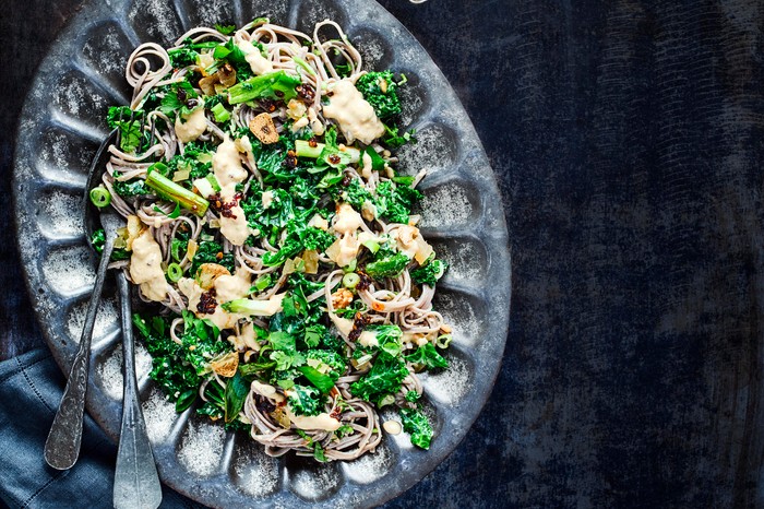 Easy Soba Noodle Recipe with Hummus and Kale served on a dark metal dish on a dark blue table