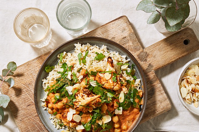 A bowl filled with chickpea and cauliflower curry and topped with flaked almonds