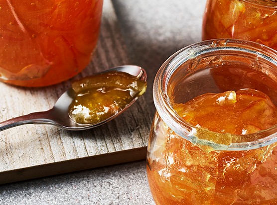 Three jars of open marmalade with a spoon on the side