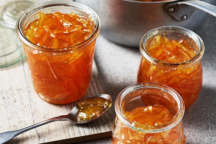Three jars of open marmalade with a spoon on the side