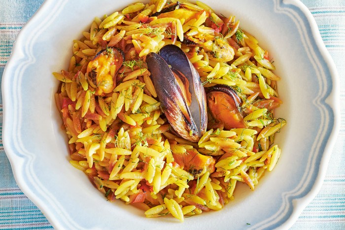 Plate of orzo with mussels topped with a mussel in a shell