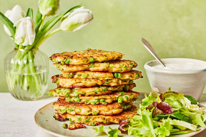 Stack of pea and halloumi fritters next to a salad