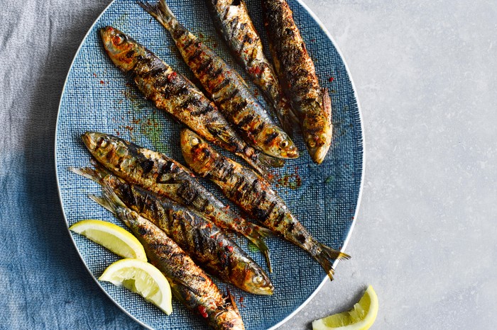 Grilled Portuguese Sardines served on an oval blue plate