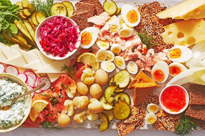 A smörgåsbord with cheese, pickles and fish on a white table